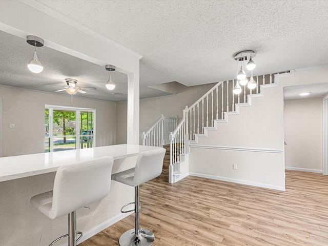 13514 Onyx Ln, Farmers Branch, TX 75234 - dining area with stairway, a ceiling fan, a textured ceiling, light wood finished floors, and baseboards