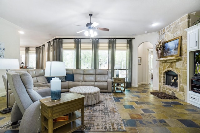 7200 Oak Creeks Ct, Fort Worth, TX 76135 - living area featuring a ceiling fan, stone tile floors, ornamental molding, a stone fireplace, and arched walkways