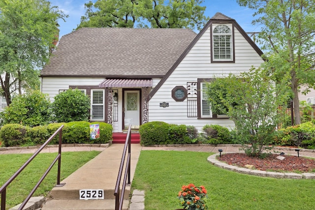 view of front facade with roof with shingles and a front lawn