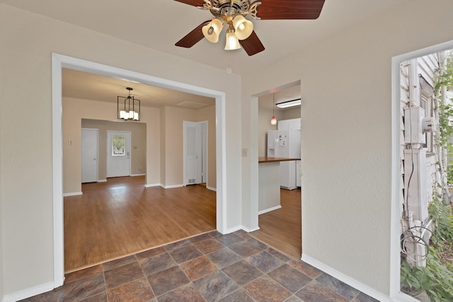 entrance foyer featuring baseboards, ceiling fan, stone finish floor, and a wealth of natural light
