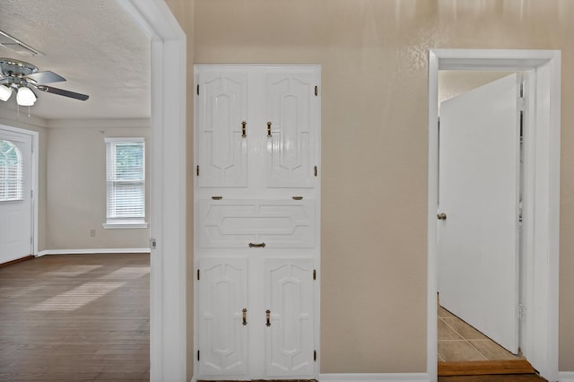 interior space featuring baseboards, a ceiling fan, and a textured ceiling