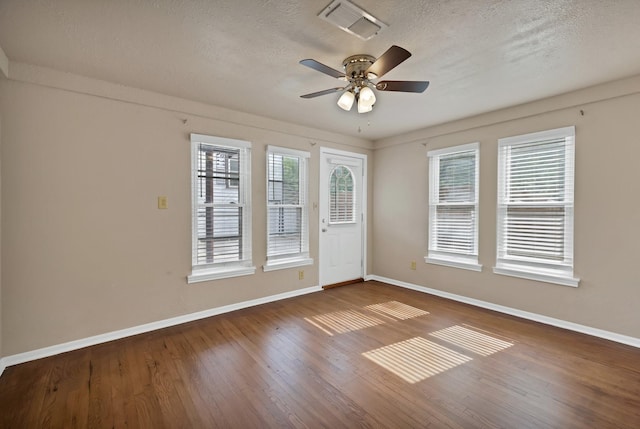 spare room with visible vents, a textured ceiling, baseboards, and wood finished floors