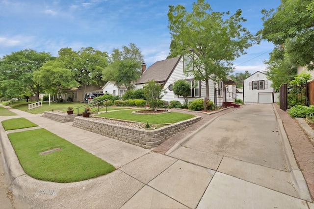 exterior space featuring an outdoor structure, a front lawn, driveway, and a residential view