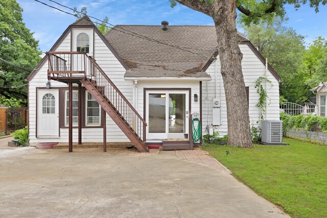 view of front of property featuring stairs, a shingled roof, a front lawn, and central AC