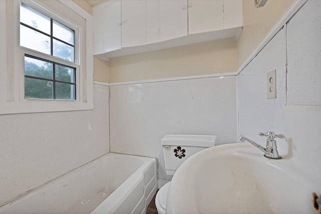 bathroom with a sink, a bathing tub, and toilet
