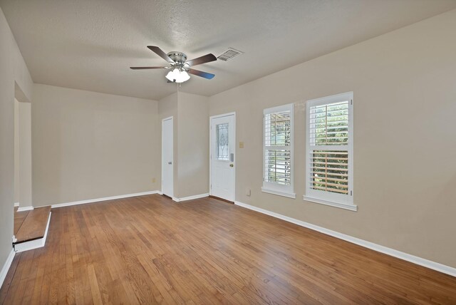 empty room with baseboards, ceiling fan, wood-type flooring, and visible vents