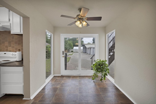 doorway to outside featuring ceiling fan, a textured wall, and baseboards
