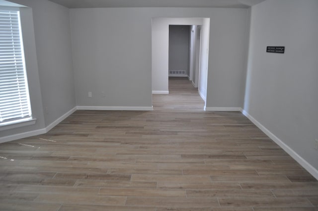 empty room featuring baseboards, wood finished floors, and visible vents