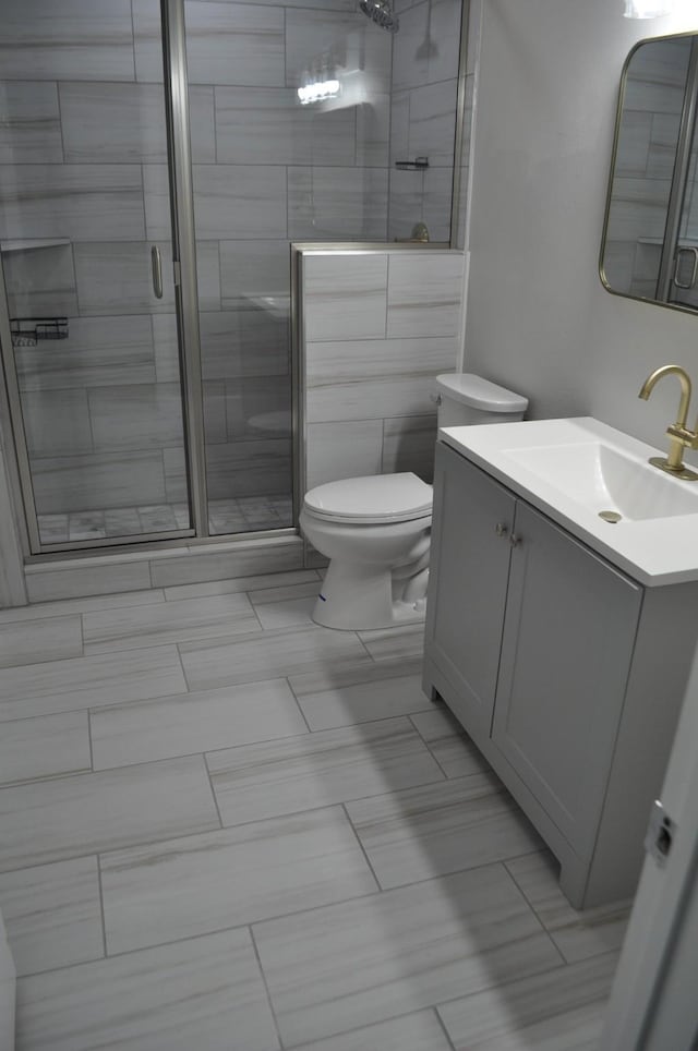 bathroom with a shower stall, toilet, and vanity