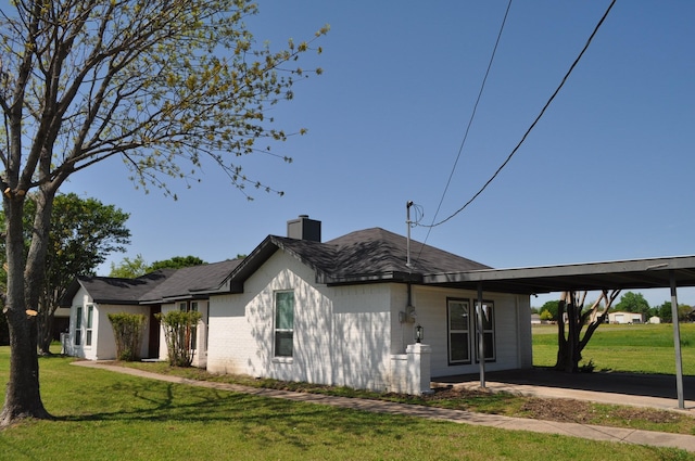 view of home's exterior featuring a yard, a chimney, and an attached carport