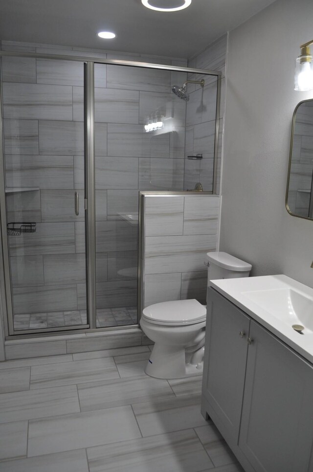 bathroom with a shower stall, toilet, vanity, and recessed lighting