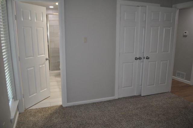 unfurnished bedroom with baseboards, visible vents, a closet, ensuite bath, and carpet floors