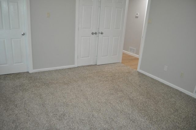unfurnished bedroom featuring baseboards, visible vents, carpet, and a closet