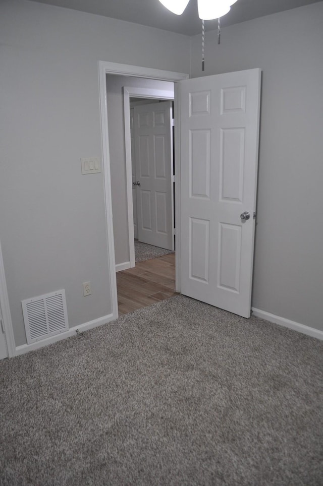 carpeted spare room featuring visible vents, a ceiling fan, and baseboards