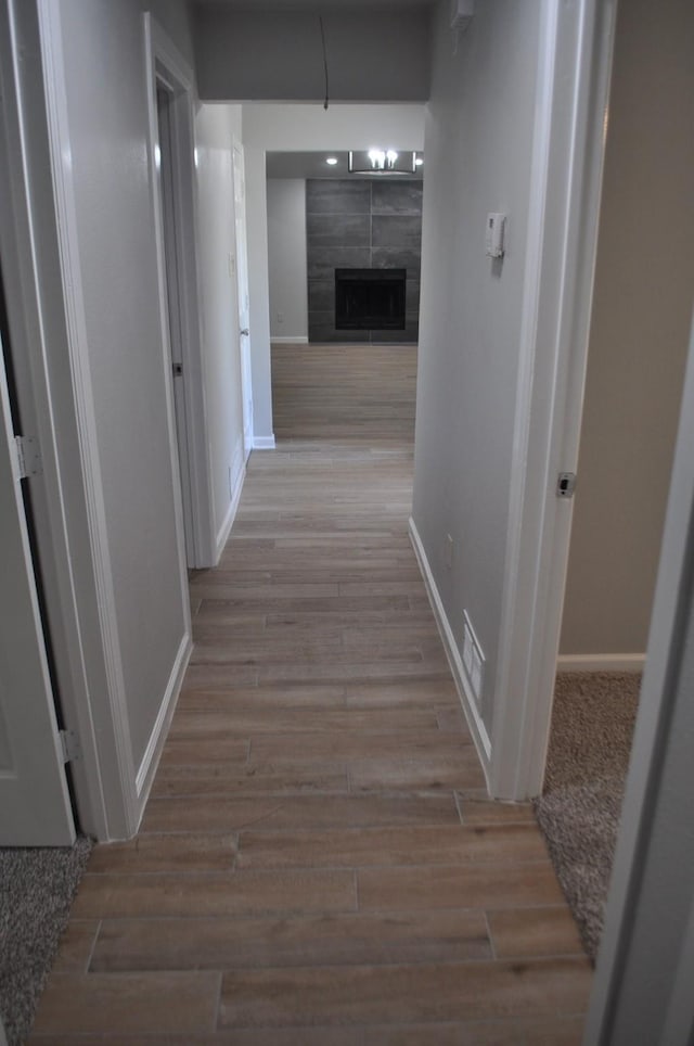 corridor featuring visible vents, wood finished floors, and baseboards