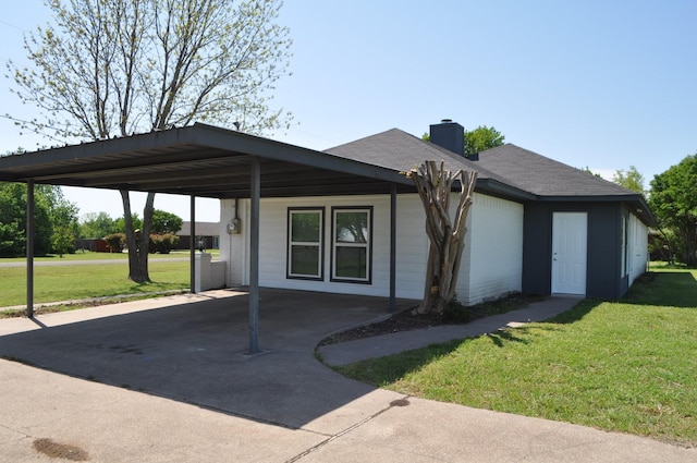 single story home featuring concrete driveway, a carport, a chimney, and a front yard