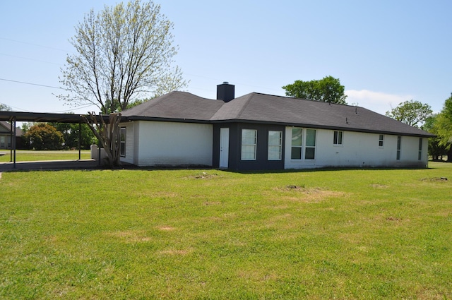 rear view of property featuring a chimney, a carport, and a yard