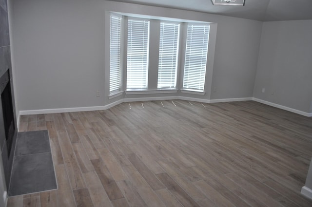 unfurnished living room featuring wood finished floors, baseboards, and a fireplace