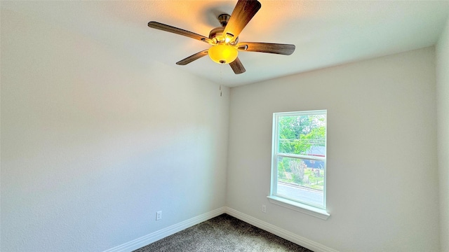 spare room featuring baseboards, a ceiling fan, and dark colored carpet