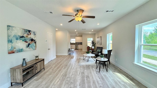 living area with baseboards, a ceiling fan, visible vents, and light wood-style flooring