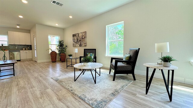living area featuring baseboards, a healthy amount of sunlight, light wood finished floors, and visible vents