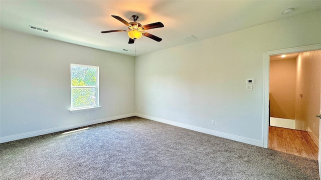 carpeted empty room with baseboards, a ceiling fan, and visible vents