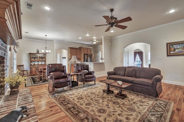 living room with a ceiling fan, arched walkways, crown molding, baseboards, and light wood-style flooring