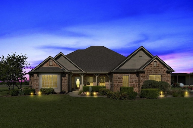 view of front of home featuring a lawn and brick siding