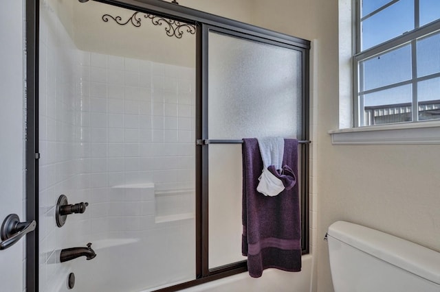 bathroom featuring enclosed tub / shower combo and toilet