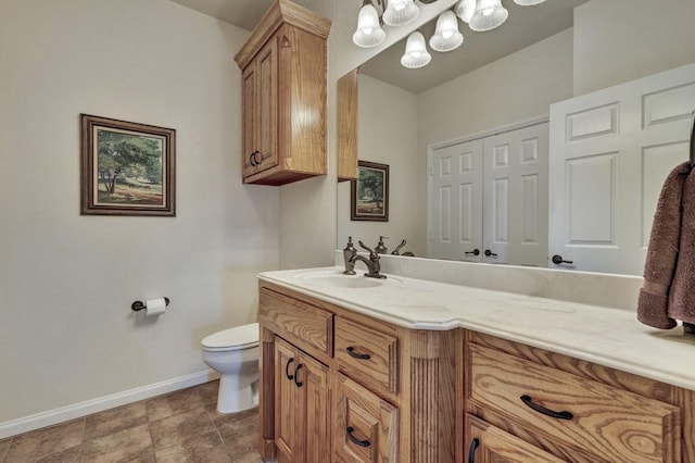 bathroom featuring baseboards, toilet, vanity, and an inviting chandelier