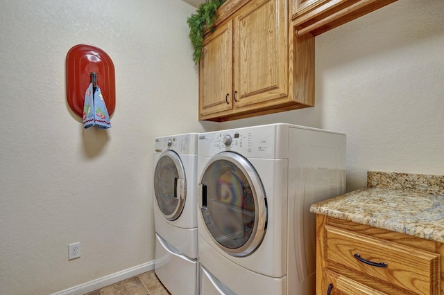 washroom featuring washing machine and dryer, baseboards, and cabinet space