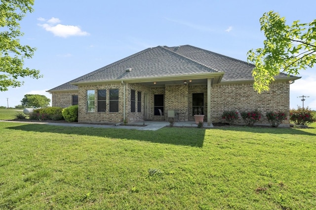 back of property featuring brick siding, a lawn, and a patio