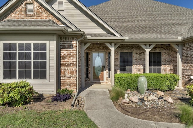 property entrance with roof with shingles and brick siding