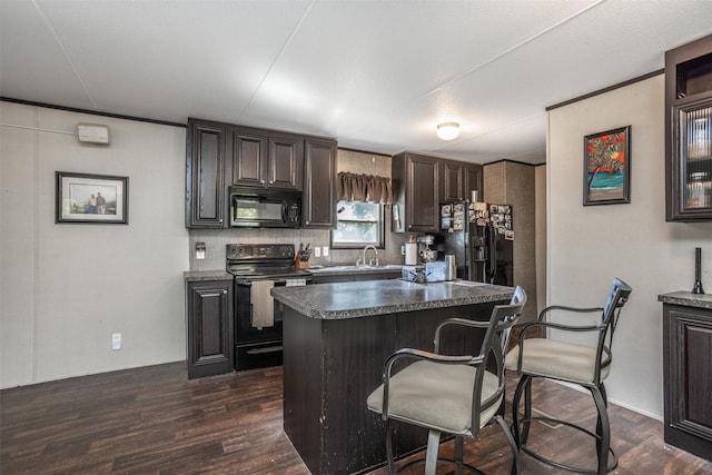 kitchen with dark wood-style floors, a breakfast bar area, a sink, and black appliances