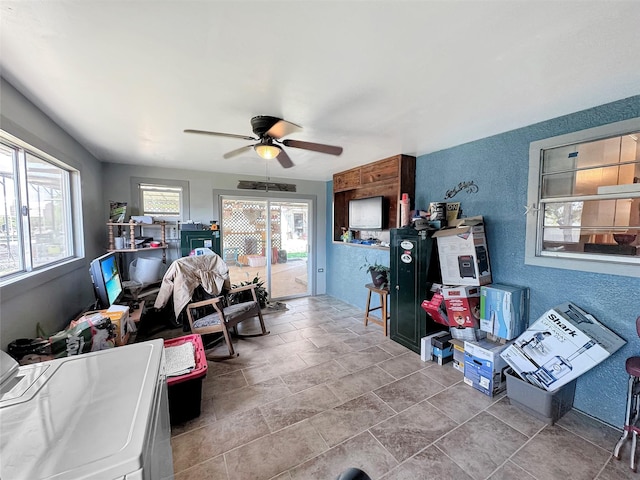 living area featuring ceiling fan, a textured wall, washer and dryer, and stone finish flooring