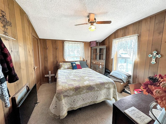 bedroom with lofted ceiling, a textured ceiling, wood walls, and light carpet