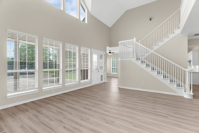 1991 Sunset Trl, Mckinney, TX 75071 - unfurnished living room with stairway, high vaulted ceiling, light wood-style floors, and plenty of natural light