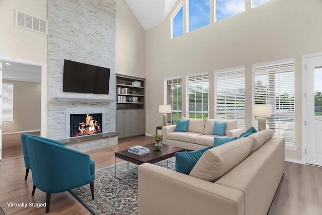 1991 Sunset Trl, Mckinney, TX 75071 - living area with a stone fireplace, visible vents, high vaulted ceiling, and wood finished floors