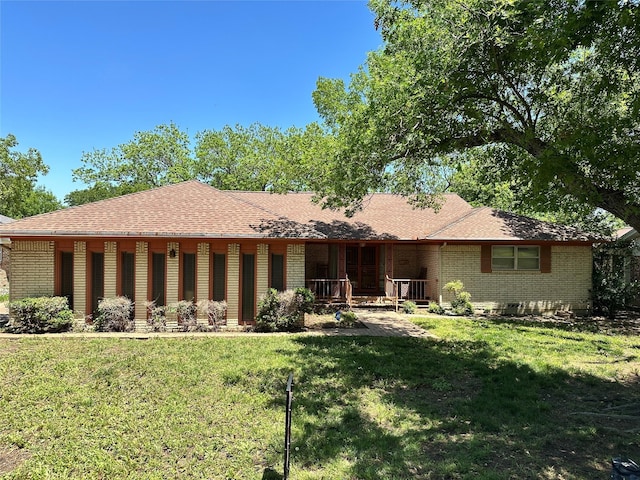 view of front of home with brick siding, roof with shingles, a porch, and a front yard