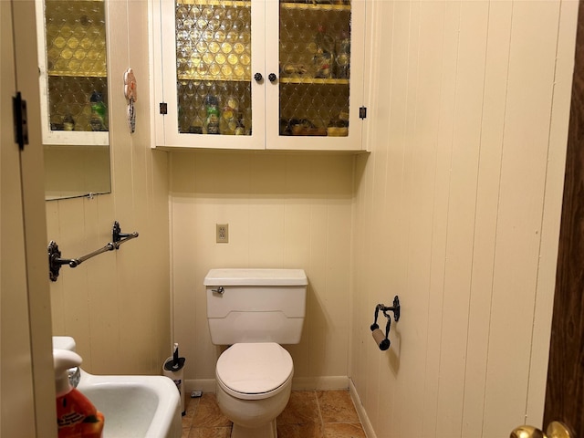 half bath featuring baseboards and toilet