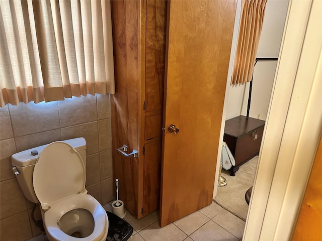 bathroom with toilet, tile patterned flooring, and tile walls