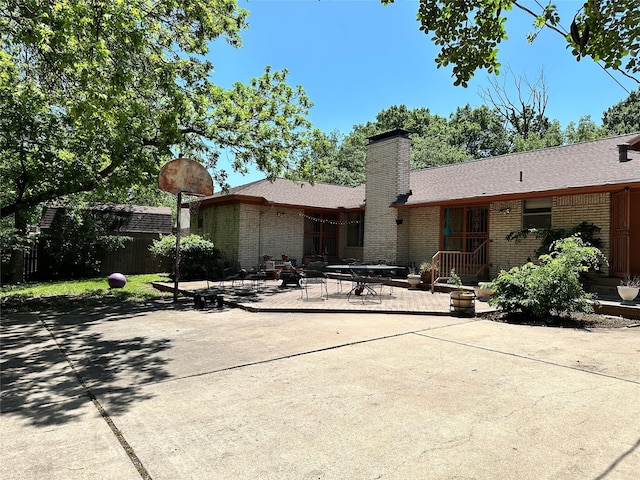 back of property featuring a chimney, brick siding, fence, and a patio area