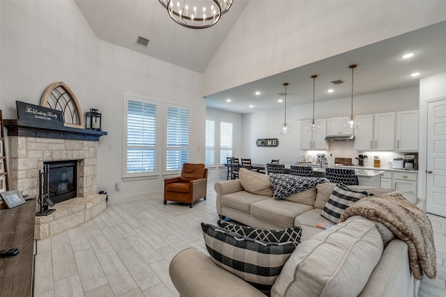 living area featuring a chandelier, baseboards, visible vents, and high vaulted ceiling