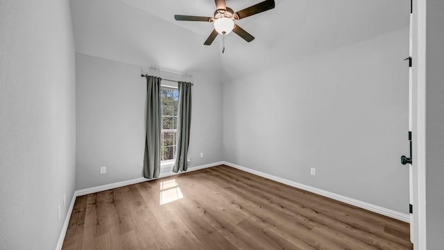 empty room with vaulted ceiling, baseboards, a ceiling fan, and wood finished floors