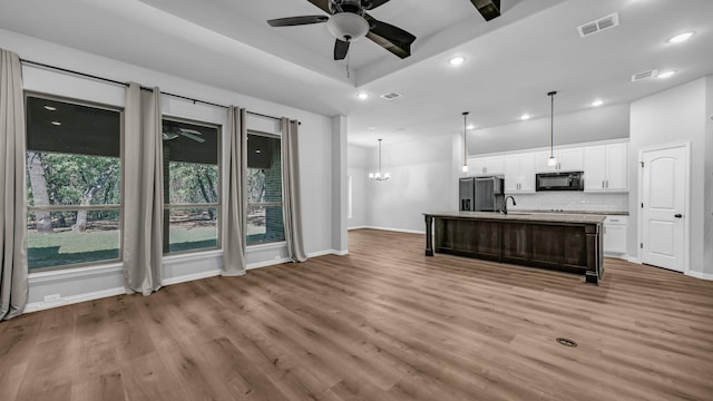 kitchen featuring ceiling fan with notable chandelier, black microwave, stainless steel refrigerator with ice dispenser, white cabinetry, and visible vents