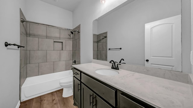full bath with shower / bathtub combination, wood finished floors, vanity, and toilet