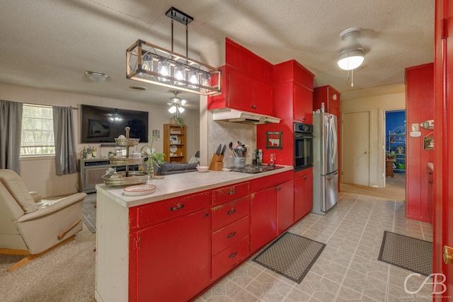 kitchen with under cabinet range hood, oven, freestanding refrigerator, and red cabinetry