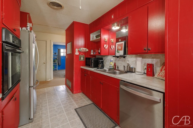 kitchen featuring red cabinets, light countertops, a sink, and black appliances
