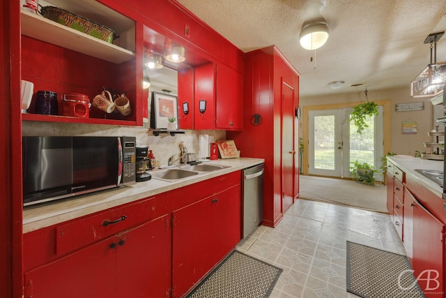 kitchen featuring stainless steel appliances, light countertops, backsplash, red cabinetry, and a sink