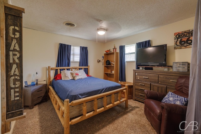 carpeted bedroom featuring visible vents, a textured ceiling, and ceiling fan